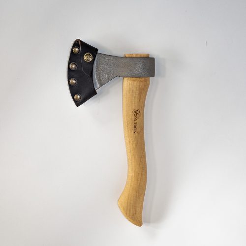 A metal axe head on a curvy wooden handle, with a leather sheath covering the edge of the axe head. The leather sheath has a metal press stud with a "W" logo embossed into it. The logo "Wood Tools" is engraved into the handle.